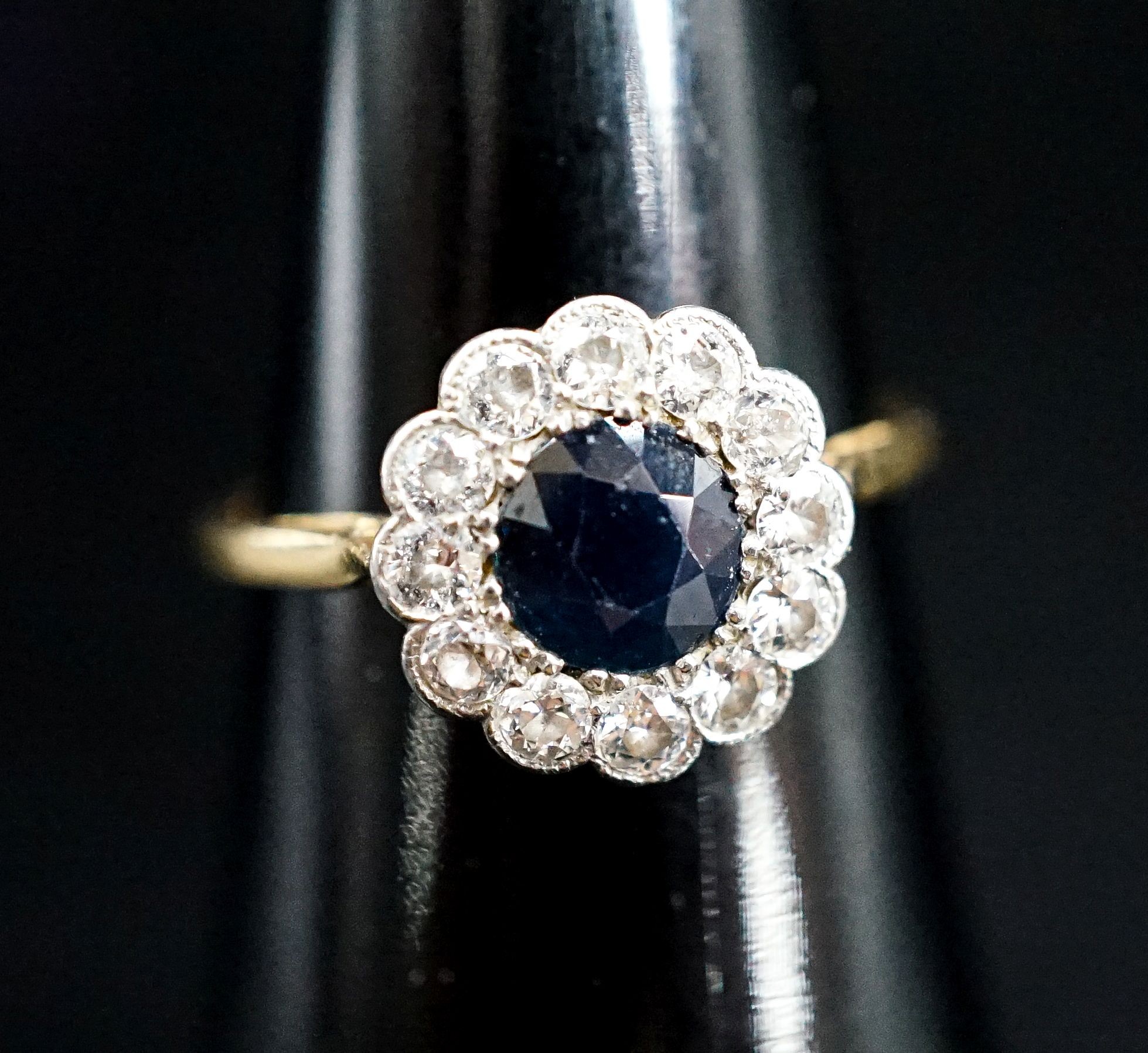 An 18ct, sapphire and diamond set circular cluster ring, size M, gross weight 2.4 grams.